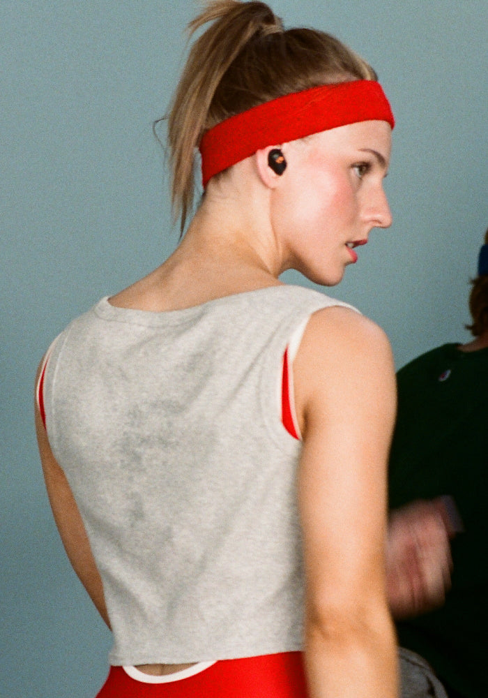 Young woman in a tank-top and headband listening to music with Skullcandy wireless sport earbuds